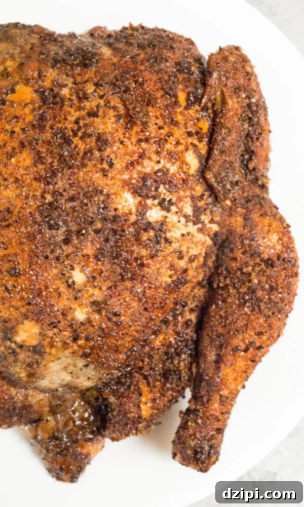 Sweet & Spicy Coffee Rubbed Smoked Chicken on white plate, garnished with fresh herbs.