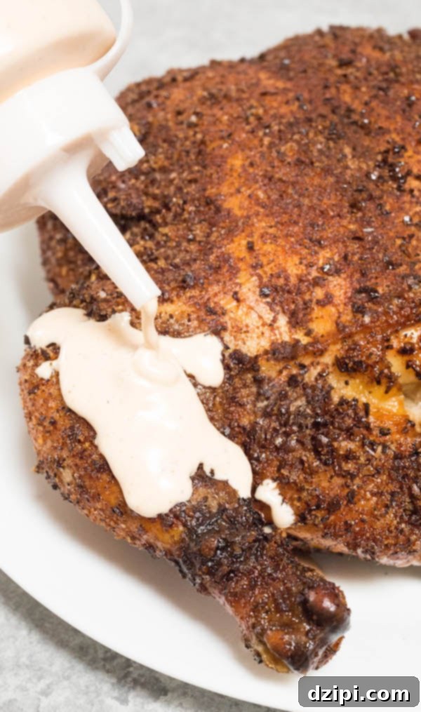 Coffee rubbed smoked chicken drizzled with creamy Alabama white sauce, ready to be served.