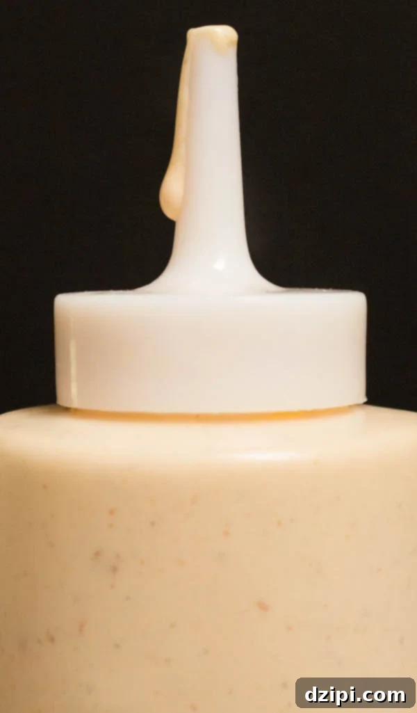 Homemade Alabama White Sauce on a black background, showcasing its creamy texture.