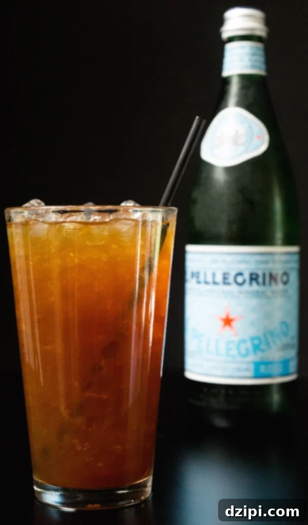 A sparkling coffee with a straw in front of a bottle of Pellegrino.