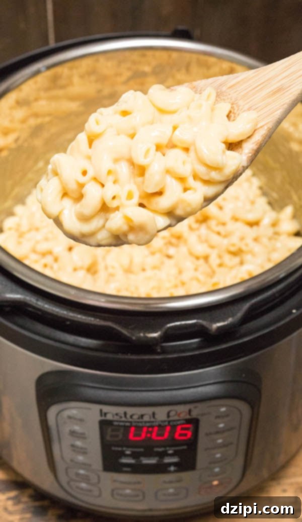 A spoon holding Instant Pot Mac & Cheese over the appliance, showcasing its creamy texture.