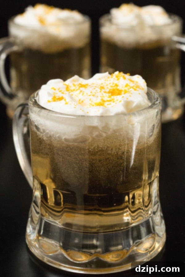 Golden Butterbeer Shots with foamy tops on a dark background.