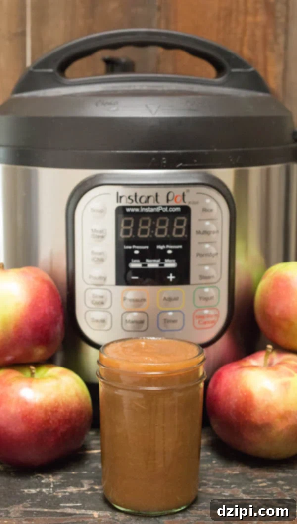 Velvety Instant Pot Apple Butter 2 A jar of Instant Pot Apple Butter in front of the appliance and fresh apples, evoking a cozy fall atmosphere.