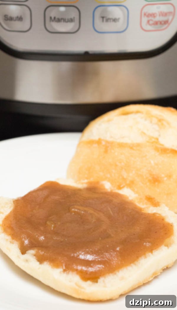 Velvety Instant Pot Apple Butter 7 Close up of a warm, fluffy roll adorned with a generous dollop of Instant Pot Apple Butter, highlighting its smooth texture and rich color.