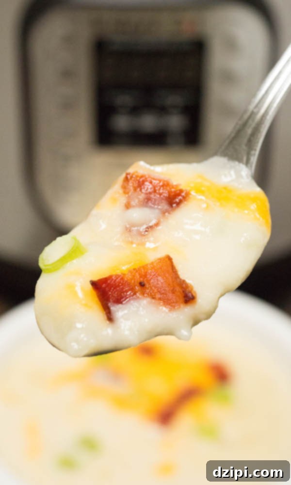 Instant Pot Ultimate Loaded Potato Soup 3 A spoonful of Instant Pot Baked Potato Soup topped with bacon, green onions, and cheese. The soup bowl and Instant Pot are out of focus in the background.