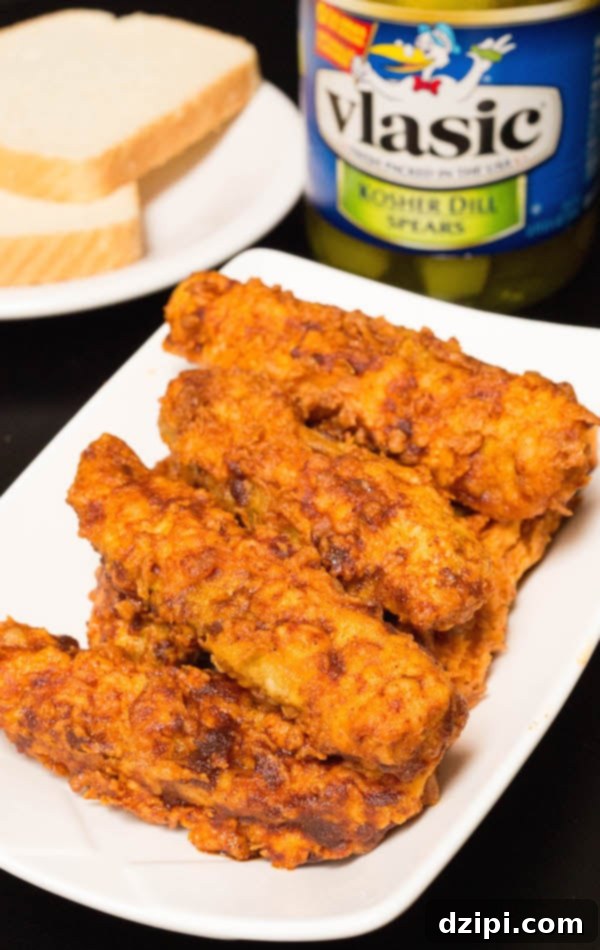 Breaded and fried pickle spears generously covered in vibrant red Nashville Hot Sauce, ready to be served.