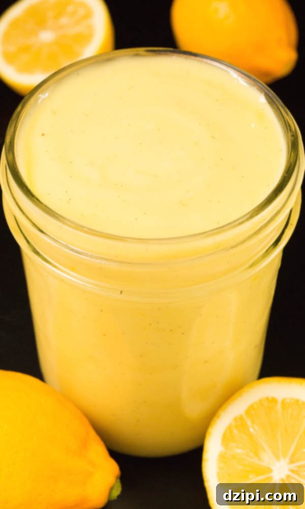 A small glass jar filled with freshly made Vanilla Bean Meyer Lemon Curd, surrounded by perfectly cut Meyer lemons.