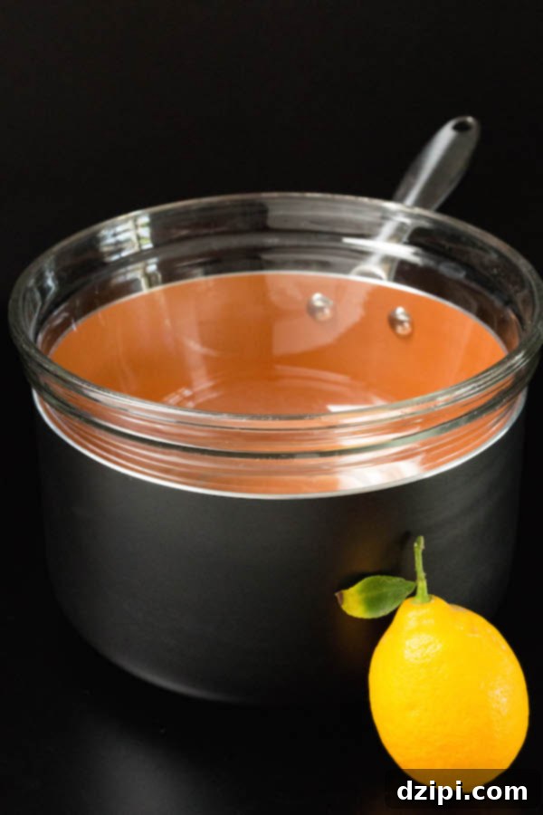 A glass bowl positioned over a saucepan, demonstrating the double boiler setup essential for making smooth Meyer Lemon Curd.