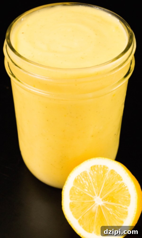 A small glass jar of Meyer lemon curd presented beautifully with a sliced lemon in front of it, ready to be enjoyed.