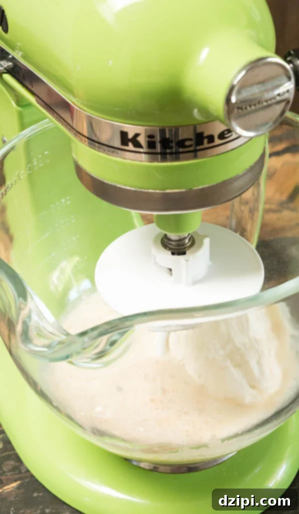 Flour being mixed in a green Kitchen Aid stand mixer.