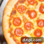 Overhead shot of a pepperoni NYC style pizza on a pizza stone.