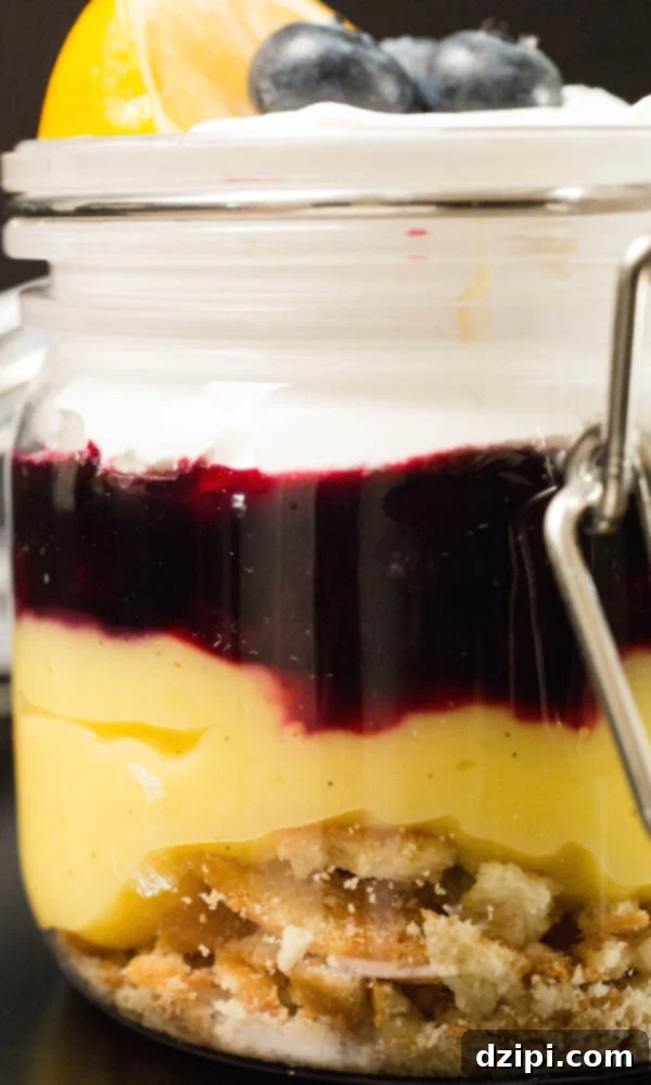 Close up shot of a Meyer Lemon & Blueberry Parfait glass, clearly showing the distinct layers of Nilla wafers, lemon curd, blueberry compote, and cool whip. 