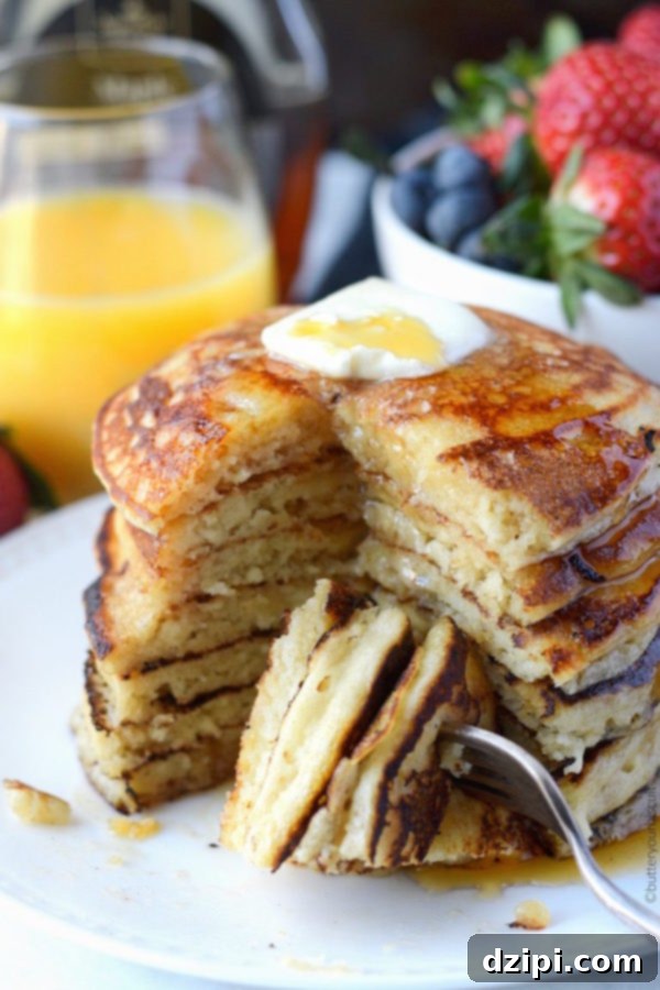 Clone Your Favorite Restaurant Meals At Home 14 Seven cooked copycat IHOP pancakes stacked on top of each other on a white plate with butter on top.