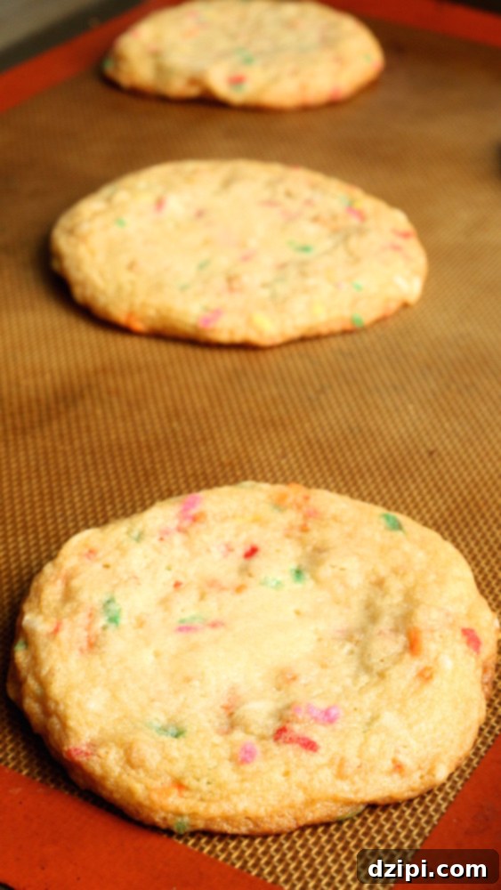 Freshly baked homemade Momofuku Confetti Cookies cooling on a baking sheet, showcasing their golden edges and vibrant sprinkle specks.
