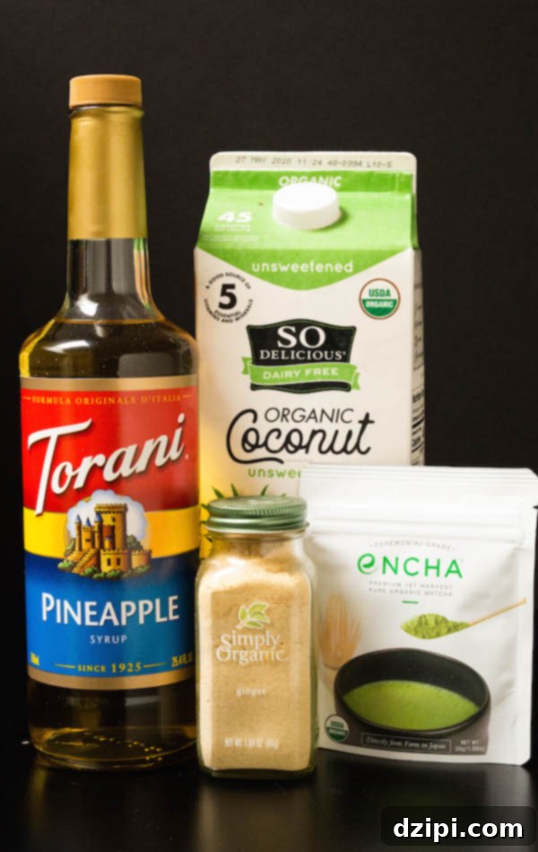 Ingredients for a homemade Starbucks Pineapple Matcha Drink laid out on a black background: coconut milk, pineapple syrup, ground ginger, and vibrant matcha powder.