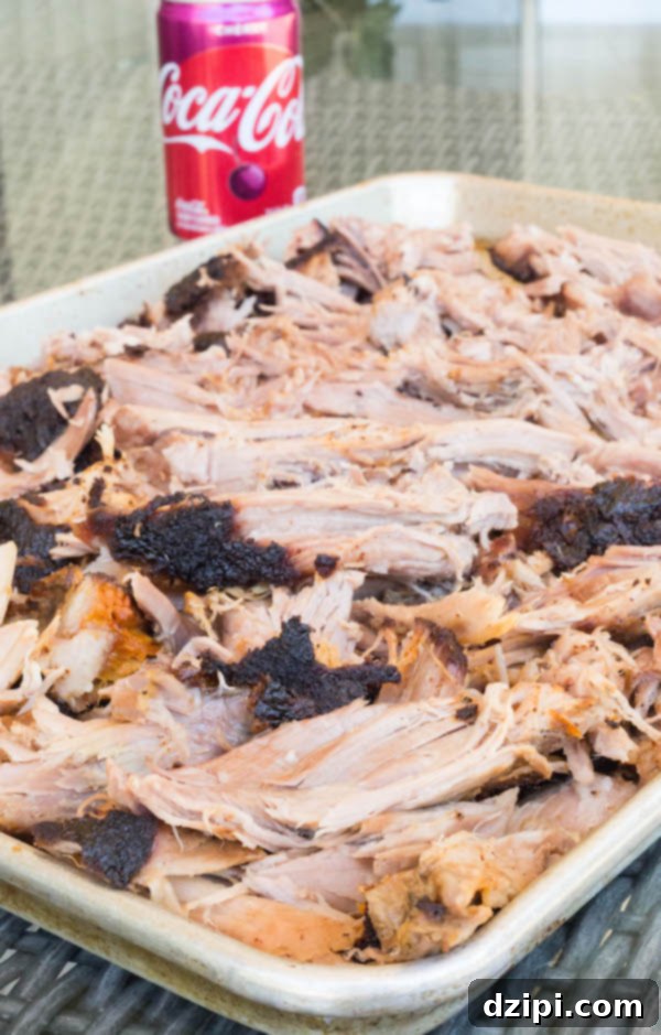 Cherry Cola Smoked Pulled Pork 11 Wide shot of Cherry Coke smoked pulled pork on a metal baking sheet, perfectly shredded and ready to serve a crowd.