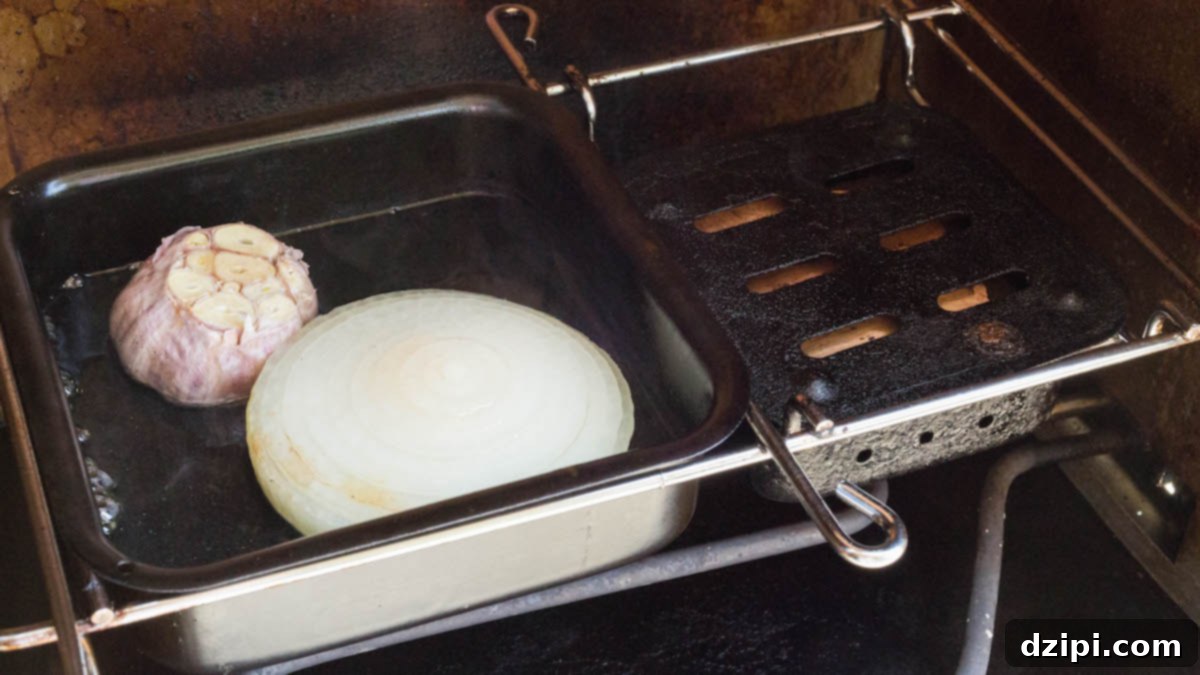 Cherry Cola Smoked Pulled Pork 4 A meat smoker's water pan filled with water, a garlic bulb, and half of an onion for aromatics.