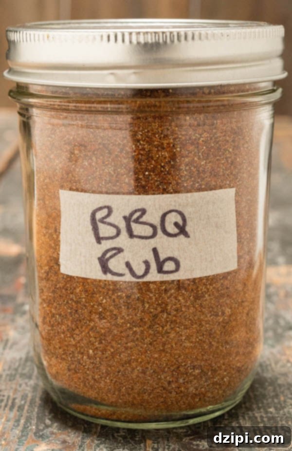 BBQ spice rub in a clear glass mason jar on a rustic wooden background, ready for grilling and smoking.