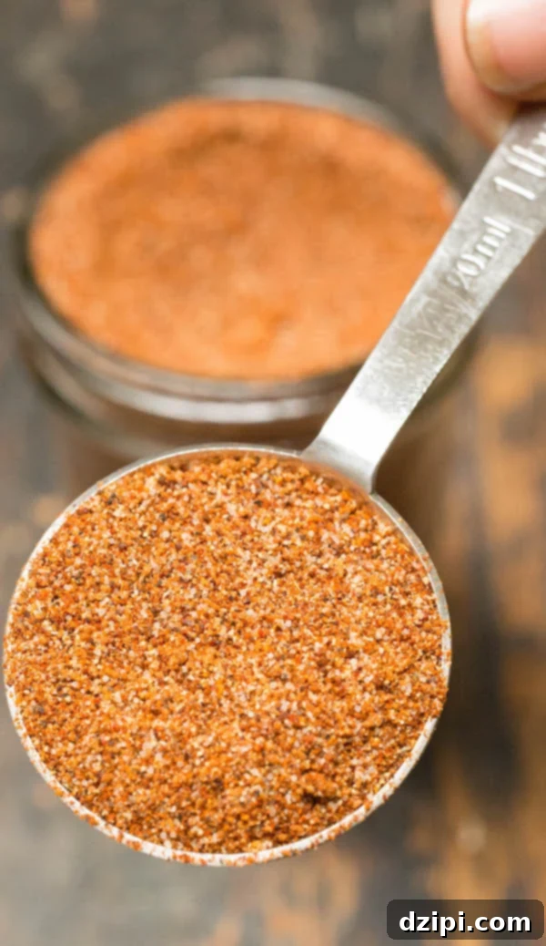 Close up shot of rich, dark BBQ spice rub in a metal tablespoon, highlighting its fine texture and vibrant color.