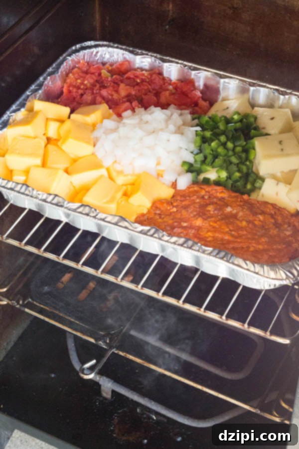 A pan of smoked queso ingredients inside an electric smoker, absorbing that delicious smoky flavor.
