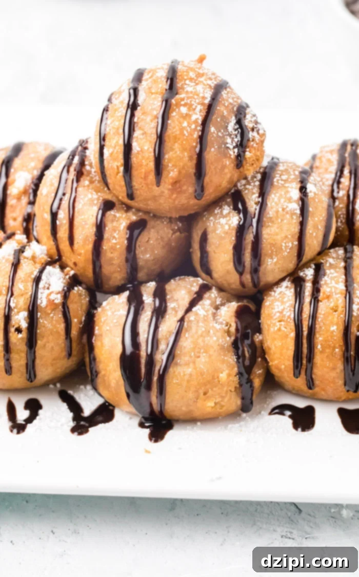 Two deep-fried cookie dough balls, one whole and one torn open to reveal the gooey chocolate chip interior, dusted with powdered sugar.
