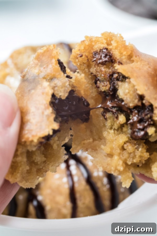 Close-up of a perfectly fried cookie dough ball being gently torn open, revealing its molten, chocolate chip-filled interior.