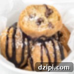 A bowl of deep-fried cookie dough balls covered in chocolate syrup and powdered sugar.
