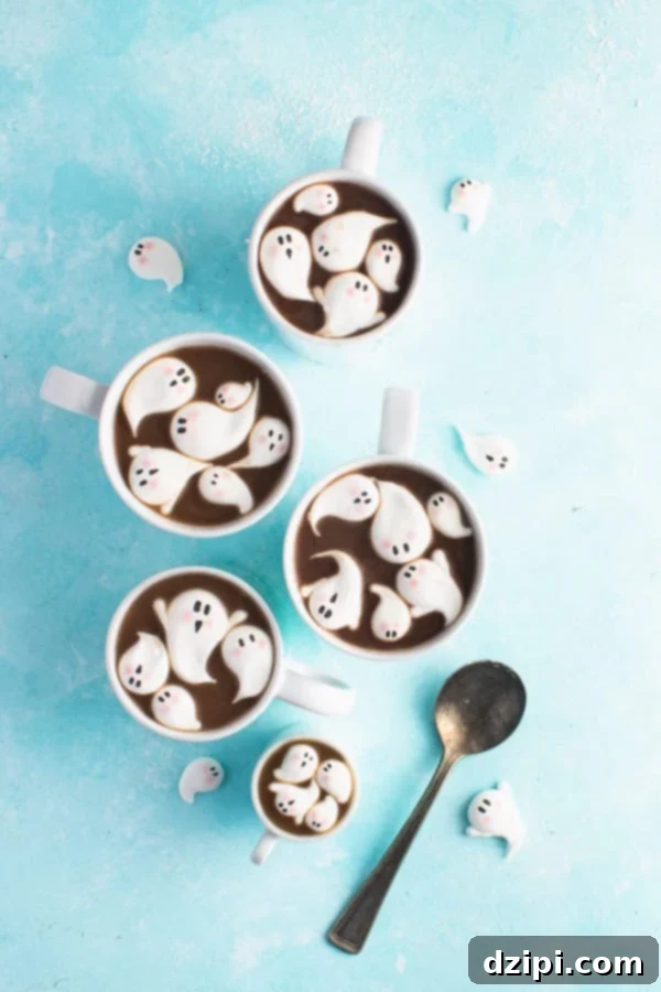 Charming ghost-shaped marshmallows with hand-drawn faces, floating on top of a warm cup of hot cocoa