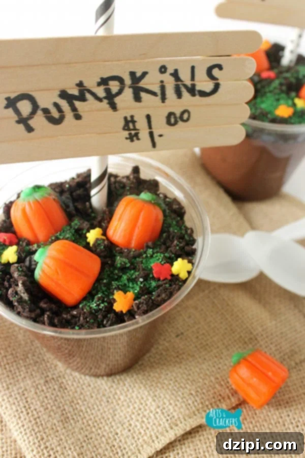 A plastic punch cup filled with creamy pudding and crushed Oreos, topped with candy pumpkins to create a miniature pumpkin patch dessert