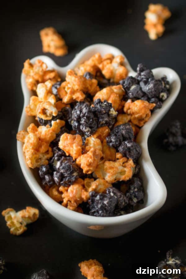 A white ghost-shaped bowl generously filled with vibrant black and orange Halloween popcorn, festive and fun