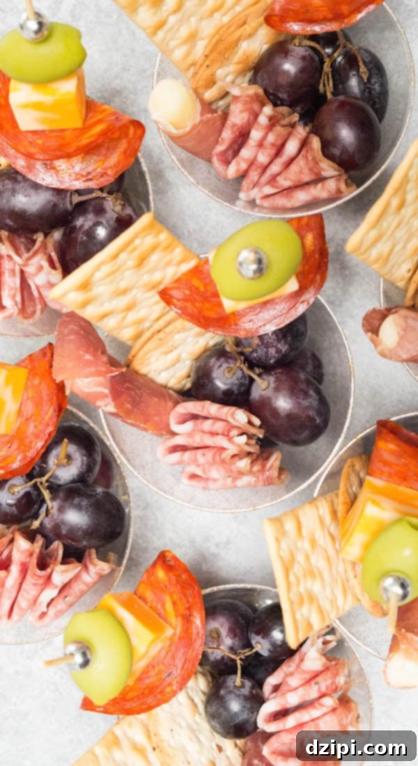 Overhead view of several beautifully arranged single-serve charcuterie cups, showcasing a variety of meats, cheeses, and grapes, ideal for easy party snacks.