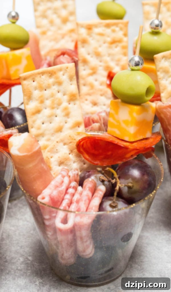 A single charcuterie cup artfully filled with salami, Monterey Jack cheese, juicy grapes, and crackers, ready to be served as a sophisticated party appetizer.
