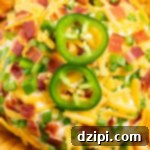 Overhead shot of a jalapeno popper cheeseball covered in shredded cheddar, diced jalapeños, and chopped bacon