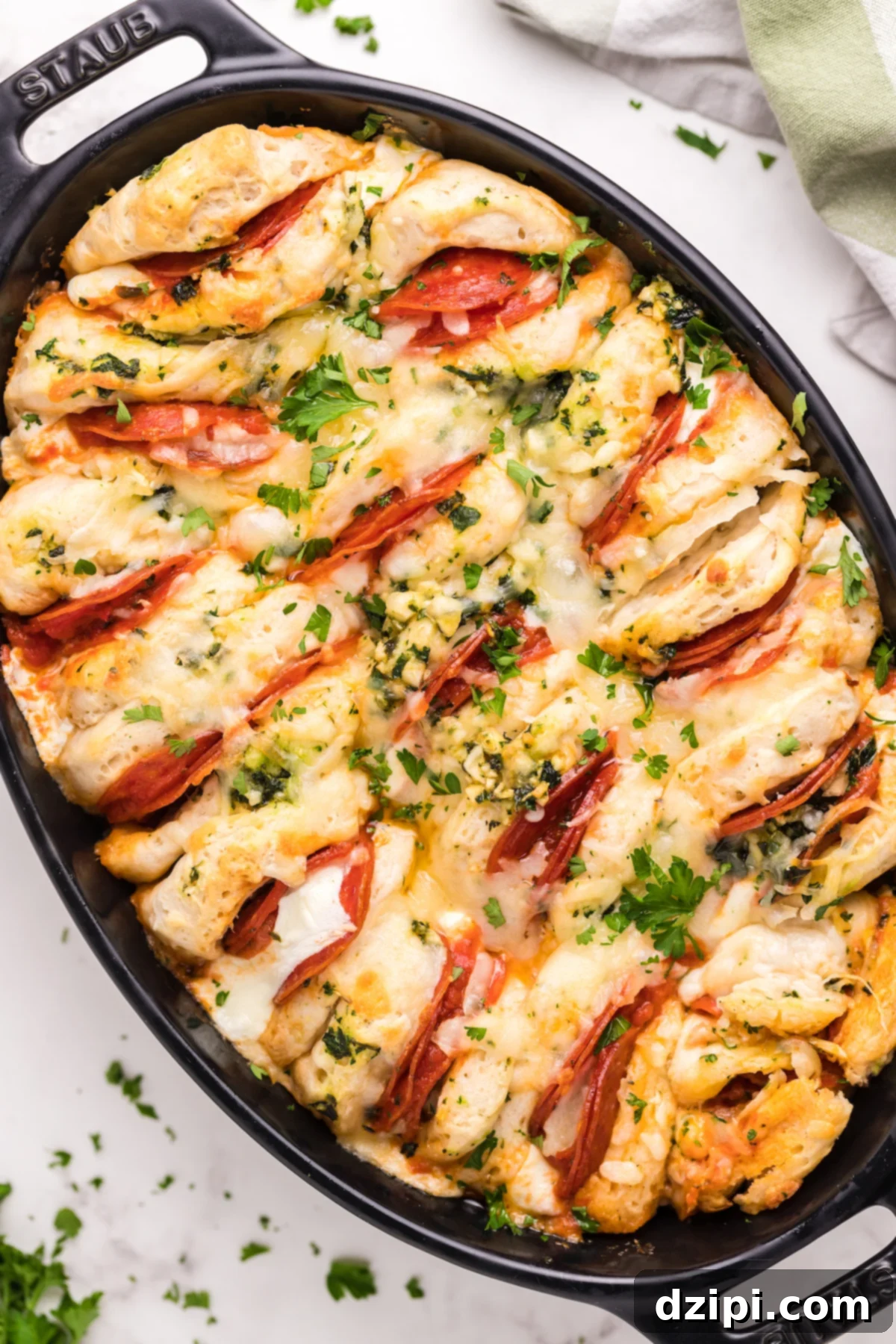 An inviting oval casserole dish brimming with golden-baked canned biscuits, each bursting with savory pizza toppings and melted mozzarella cheese, fresh out of the oven.