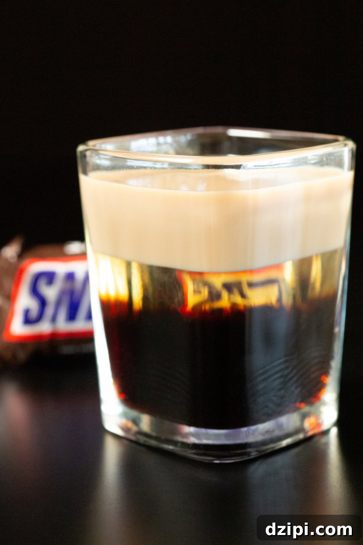 Snickers Shooter 2 A square shot glass is filled with a Snickers shot, revealing three distinct, beautifully layered liqueurs.