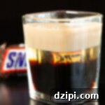 Snickers Shooter 6 A square shot glass is filled with a snickers shot. You can see the three distinct liqueurs layered.