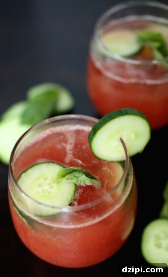 Vibrant Cucumber Watermelon Basil Refresher 4 A close-up of the Cucumber Watermelon Basil Cooler in a glass, with a basil leaf and cucumber slice garnish.