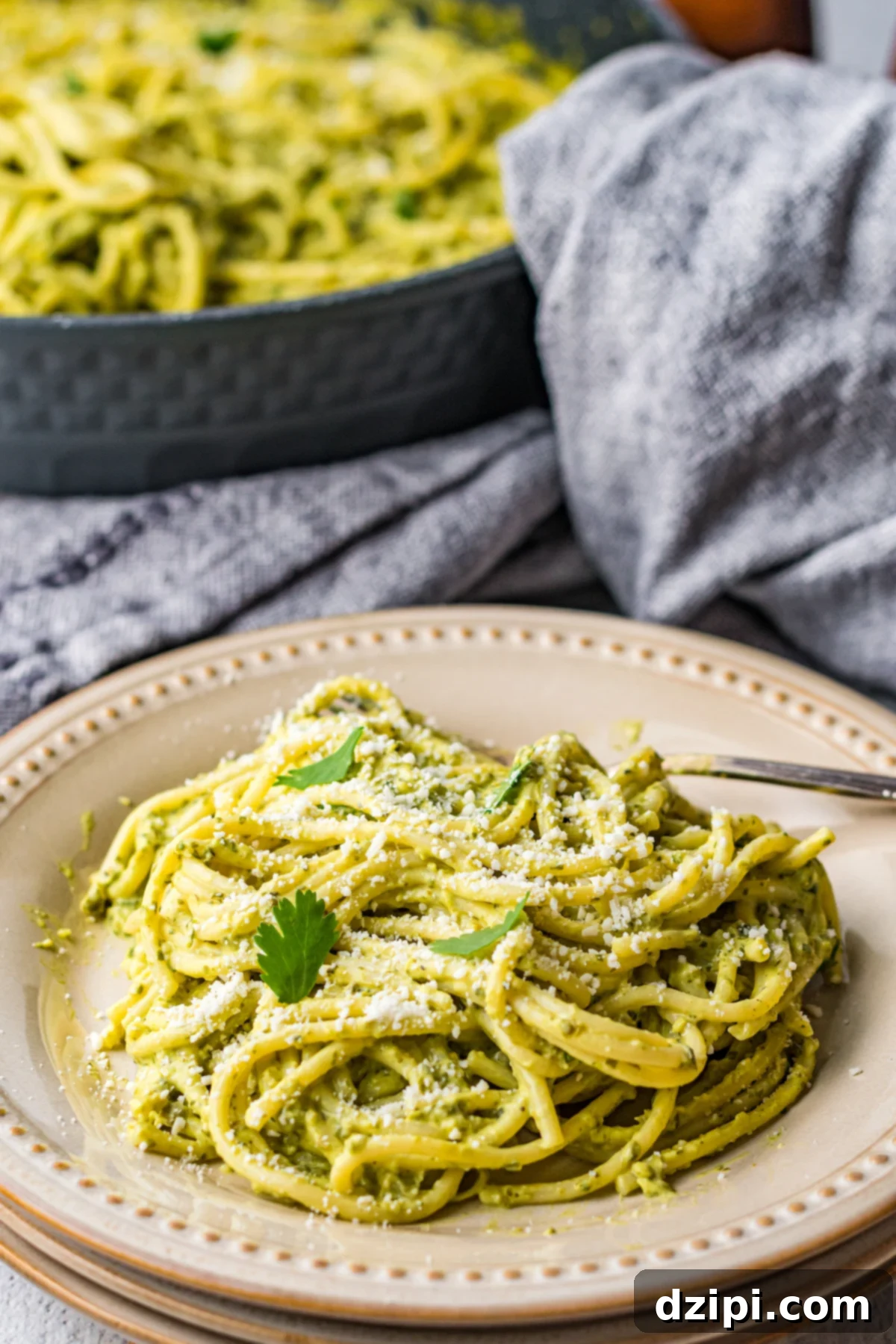 A beautifully plated serving of green Mexican spaghetti sits invitingly in front of a large pan brimming with more of the same delicious dish.
