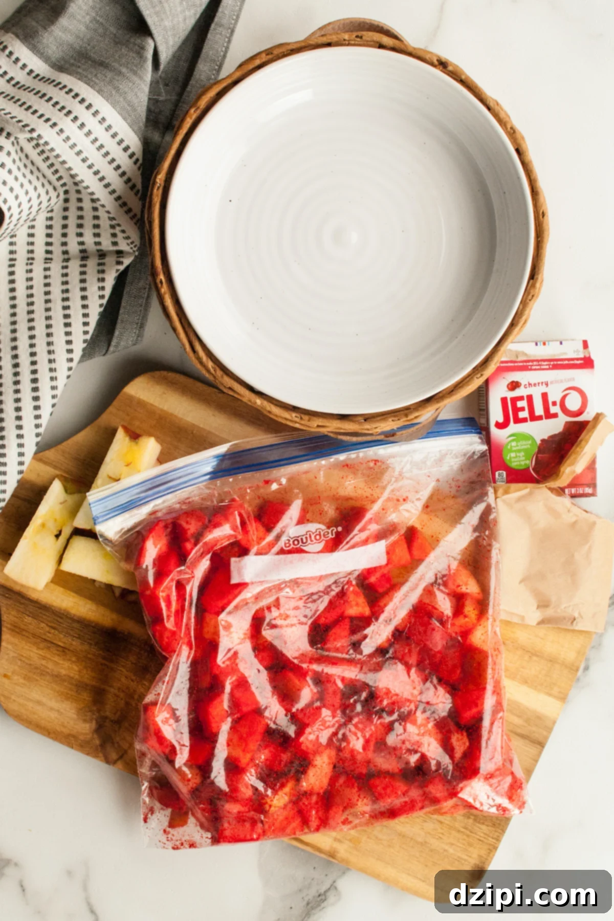 Overhead view of chopped apples that have been put in a ziploc bag and covered with red cherry jello powder
