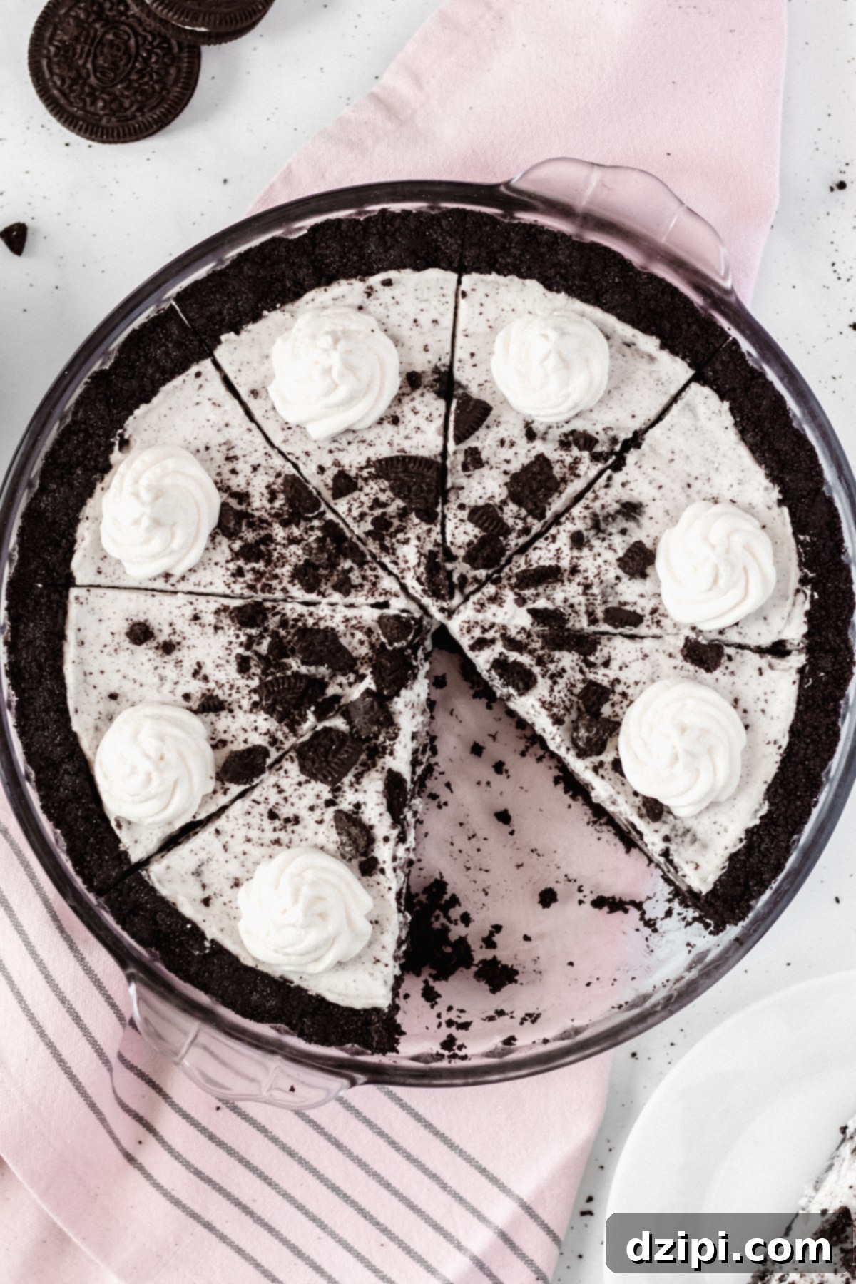 Decadent Oreo Cream Pie 2 Overhead view of a cookies & cream oreo pie in a glass pie dish. A slice has been removed, showcasing the creamy filling and dark crust.