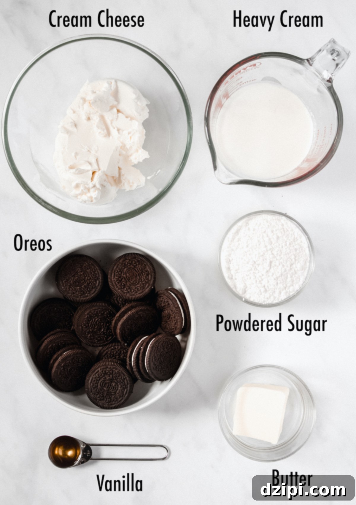 Decadent Oreo Cream Pie 4 Overhead view of the ingredients needed for cookies and cream pie: blocks of cream cheese, a carton of heavy cream, a stack of Oreo cookies, sticks of butter, a bottle of vanilla extract, and a bowl of powdered sugar.