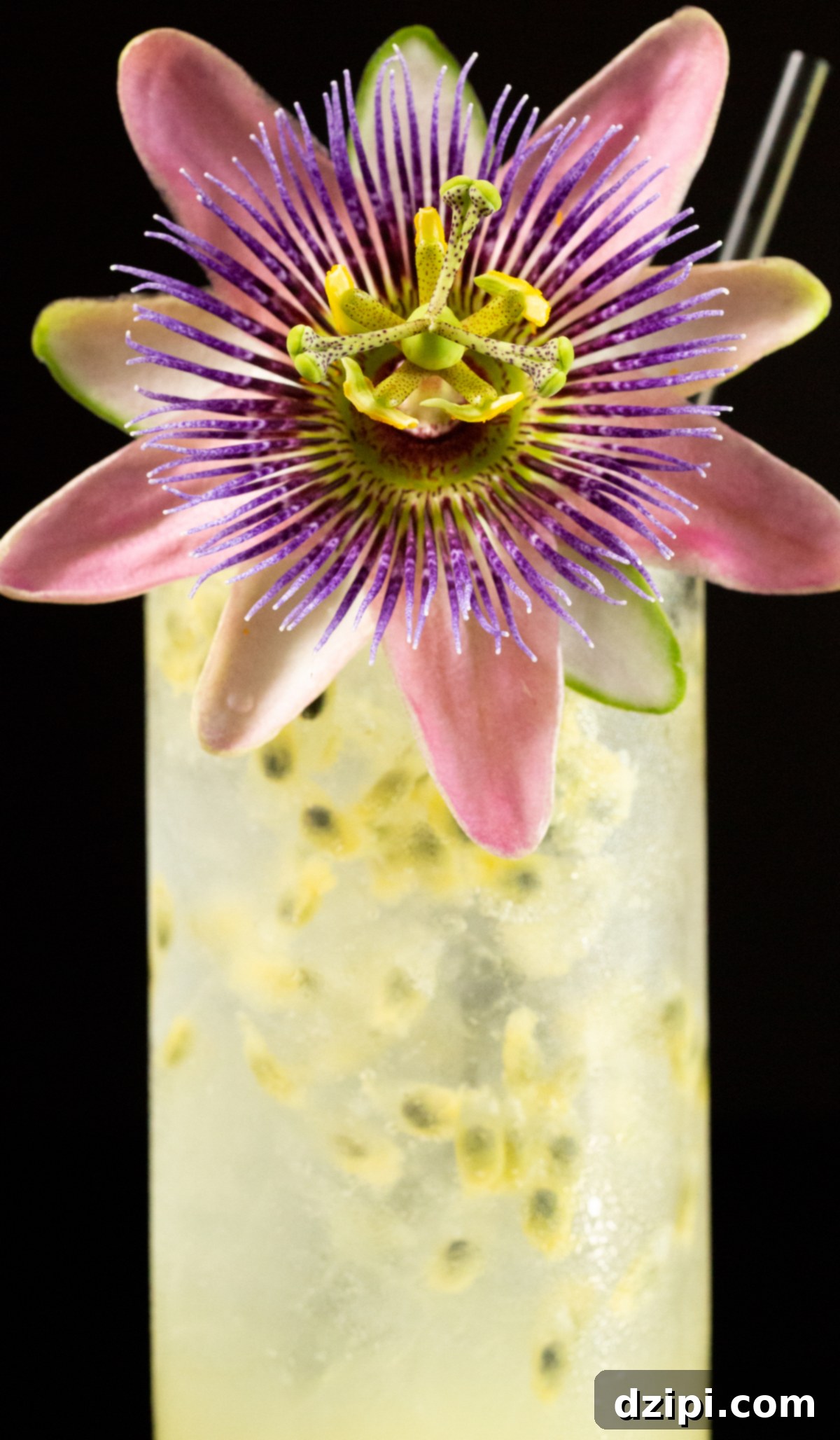 A vibrant passion fruit cocktail, garnished with a passion fruit flower and a black straw, sits ready to be enjoyed.