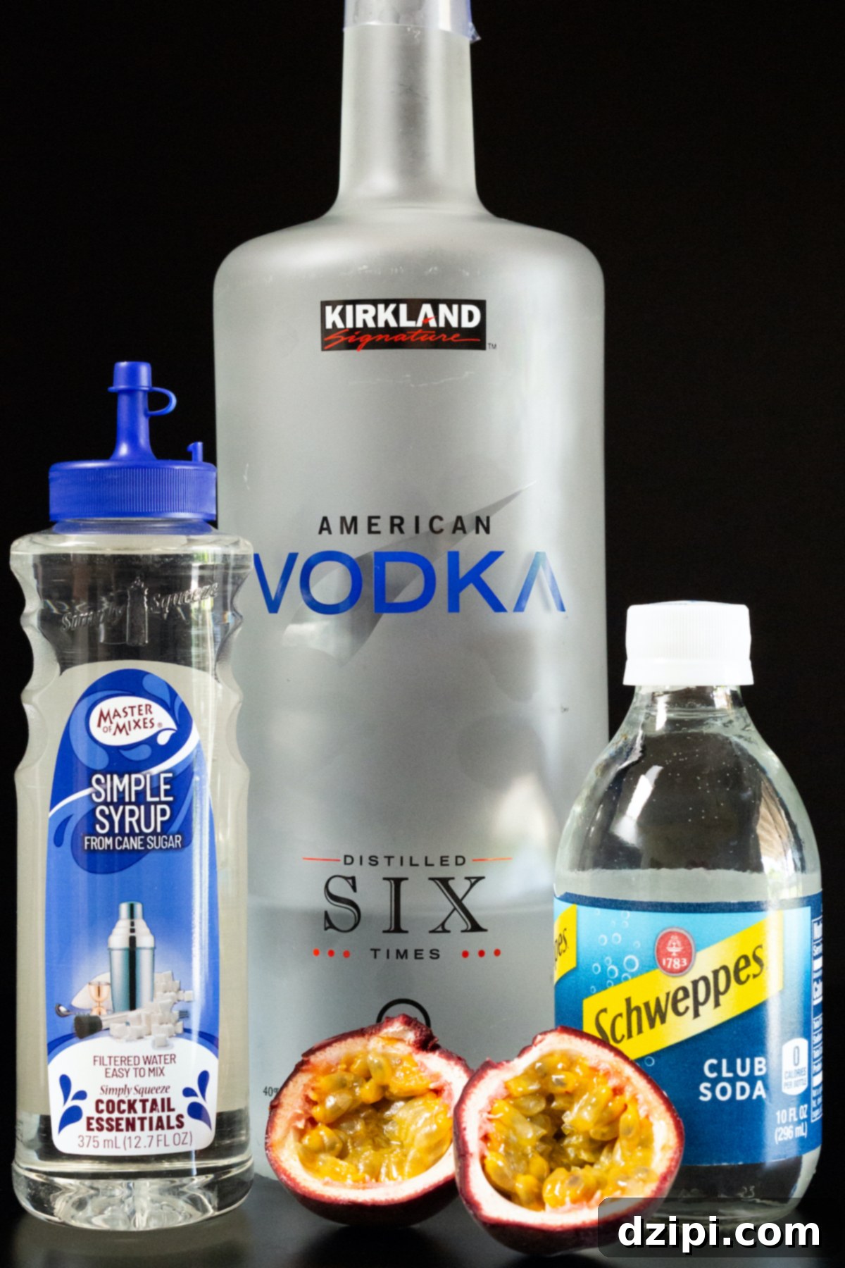 The vibrant ingredients for a passion fruit cocktail beautifully arranged on a dark background: a bottle of simple syrup, a bottle of vodka, a bottle of club soda, and a fresh passion fruit, artfully sliced in half to reveal its enticing pulp.