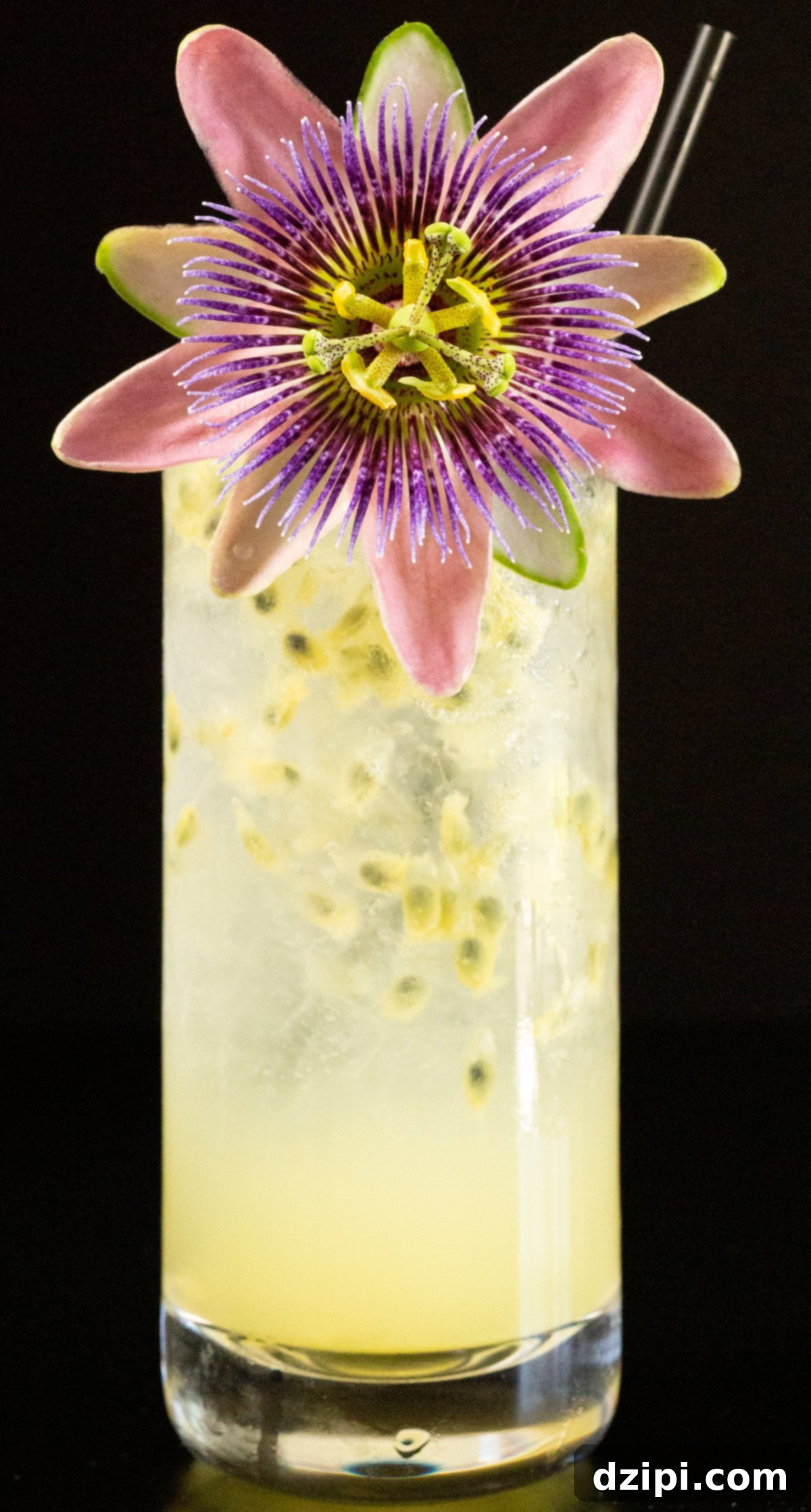A stunning passion fruit cocktail, served in a sleek highball glass and elegantly garnished with a delicate passion fruit flower, embodies the essence of a refreshing tropical escape.