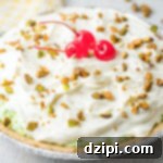 Emerald Dream Pie 7 An uncut pistachio pie topped with whipped cream, chopped pistachios, and maraschino cherries.