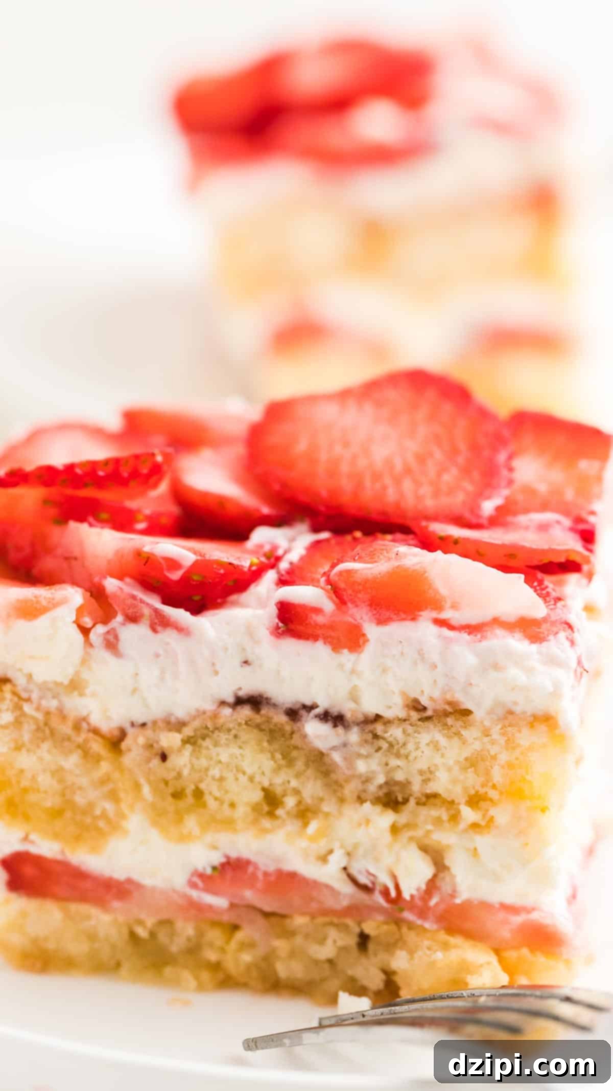 A close-up view of a slice of Strawberry Tiramisu, revealing exquisite layers of delicate ladyfingers, fresh strawberries, and rich, creamy filling.