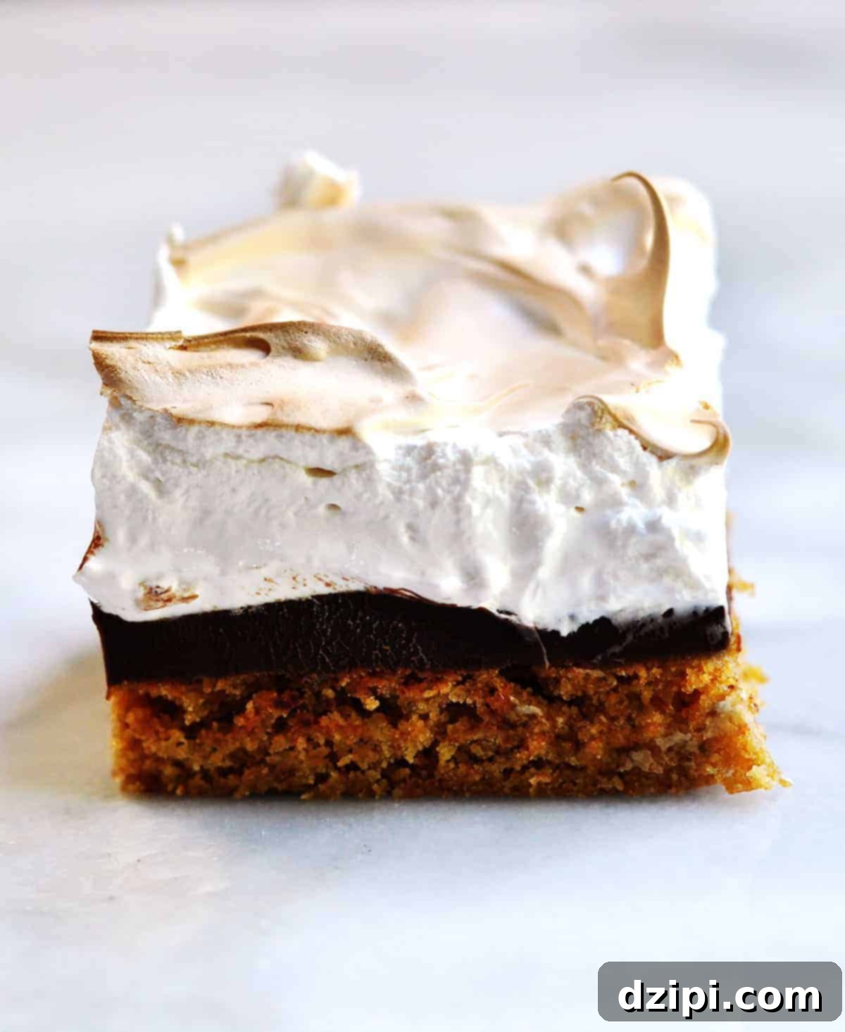 A delicious s'mores brownie bar featuring distinct layers of graham cracker, rich chocolate, and perfectly toasted marshmallow meringue.