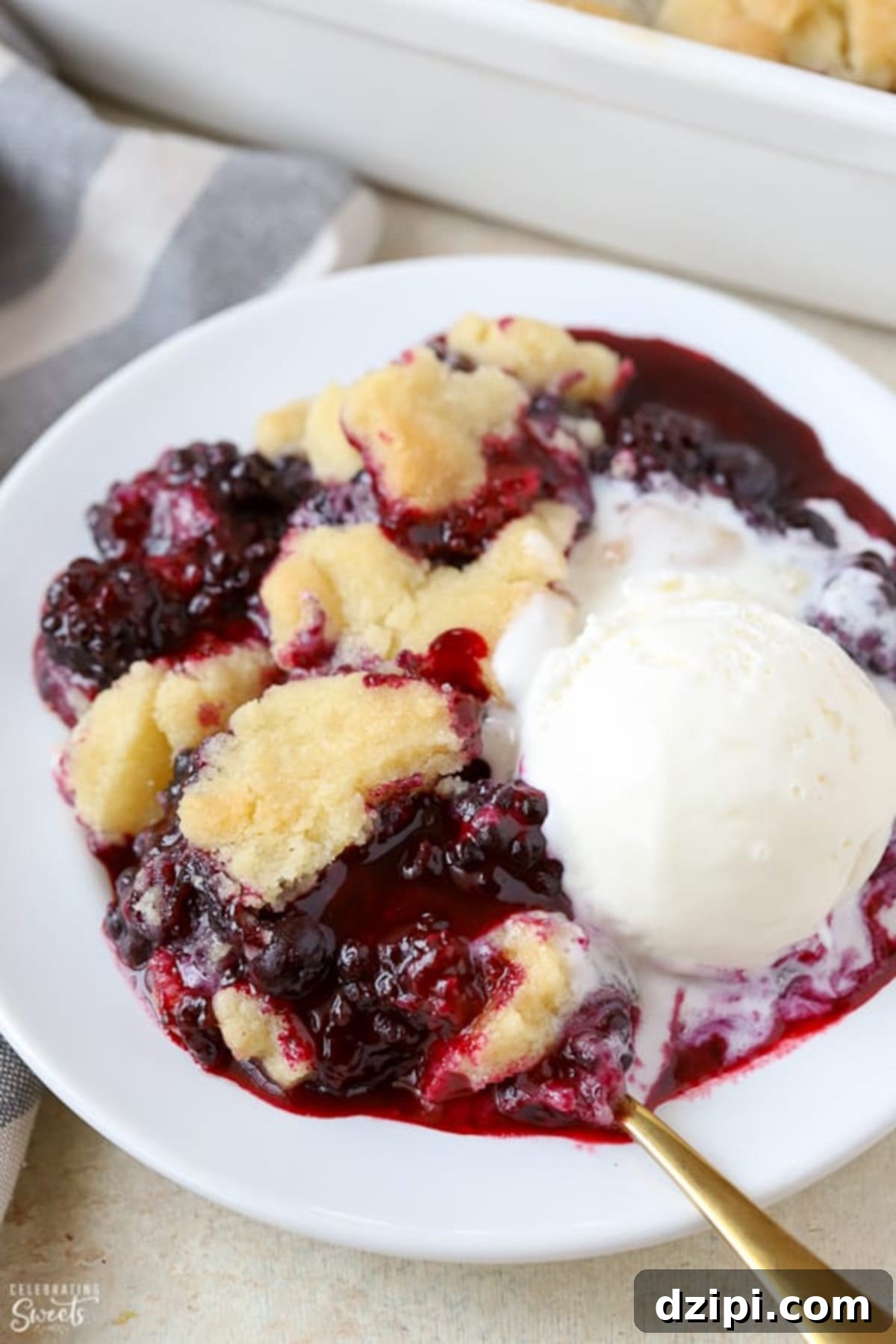 A comforting bowl of blackberry cobbler served with a scoop of vanilla ice cream that has begun to melt, highlighting its warm and delicious appeal.