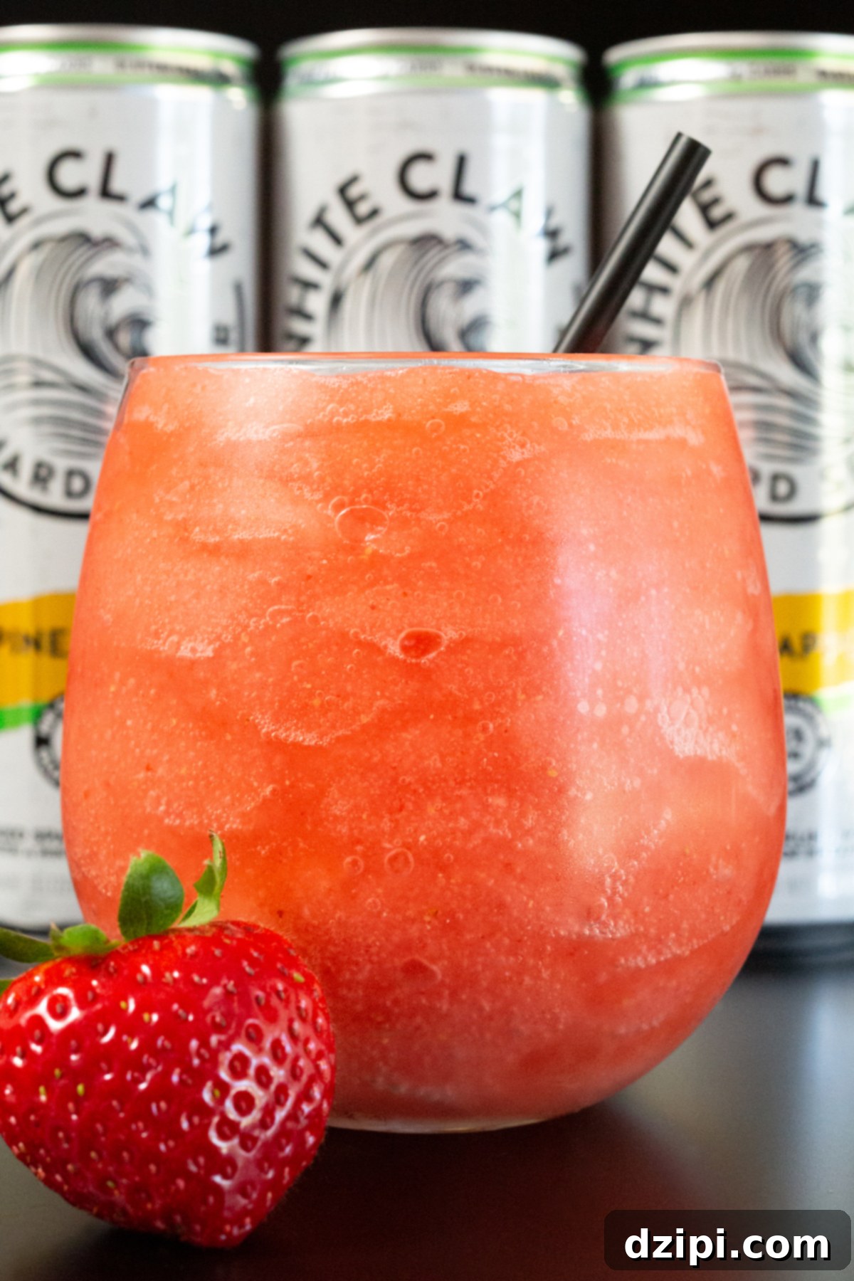 Closeup of a wine glass filled with a pink colored white claw slushie.