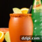 A clay jar that's filled with a cantarito cocktail is garnished with a lime & orange slice. It sits on a black background next to a glass bottle of squirt soda and sliced grapefruit, orange, and lime.